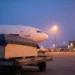 Транспортный ящик на грузовой тележке у самолёта в аэропорту на рассвете