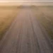 Leere Landstraße durch weite Felder in Osteuropa im Morgennebel bei Sonnenaufgang