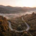 Kurvige leere Bergstraße durch herbstliche Wälder der Karpaten mit Nebel in den Tälern