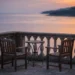 Leere Hotelterrasse mit zwei Stühlen und kleinem Tisch mit Blick auf das ruhige Meer im Abendlicht